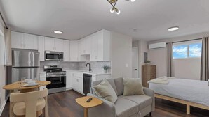 A compact living space with a kitchenette, a sofa, a dining table, and a bed. - New Columbus Studio Steps from Downtown (Columbus)