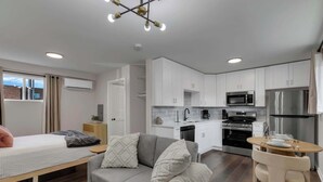 Eine moderne Wohnung mit Küchenzeile, einer Couch, einem Esstisch und einem Bett.