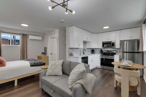 Un apartamento moderno con kitchenette, sofá, mesa de comedor y cama.