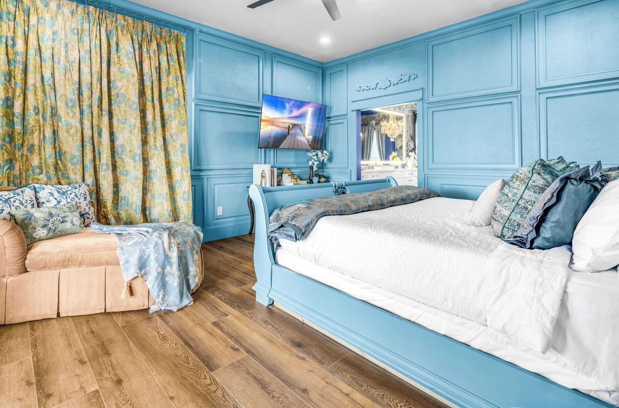 A bedroom with a bed, a sofa, a TV, and a mirror.
