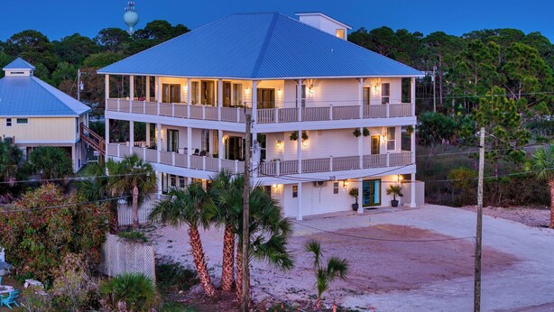Ein zweistöckiges Strandhaus mit Balkonen, einer Veranda und Blick auf den Ozean.