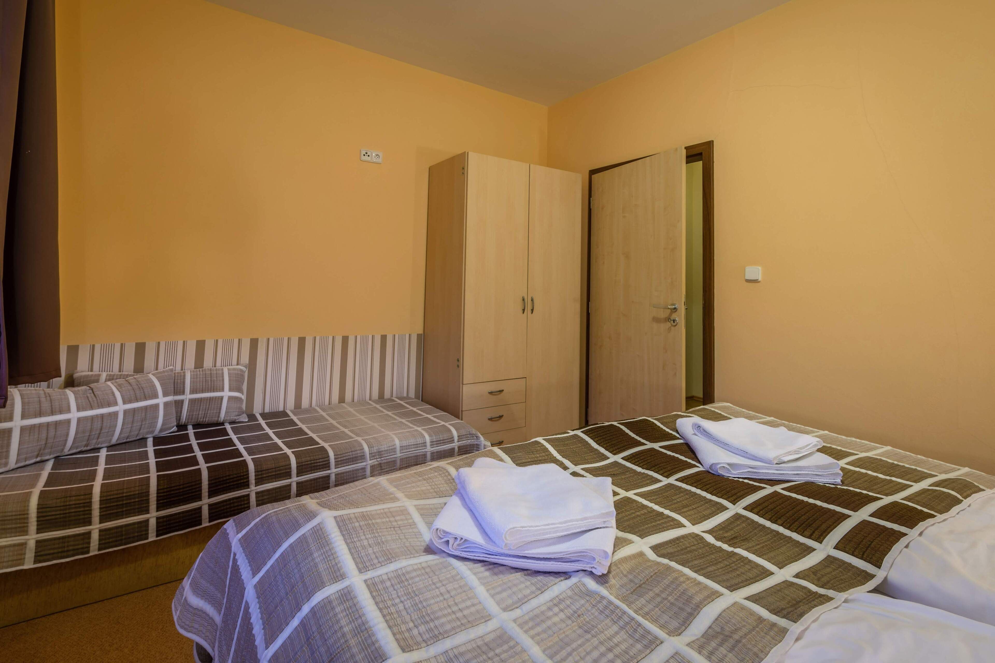 A hotel room with two beds, a wardrobe, and a door.