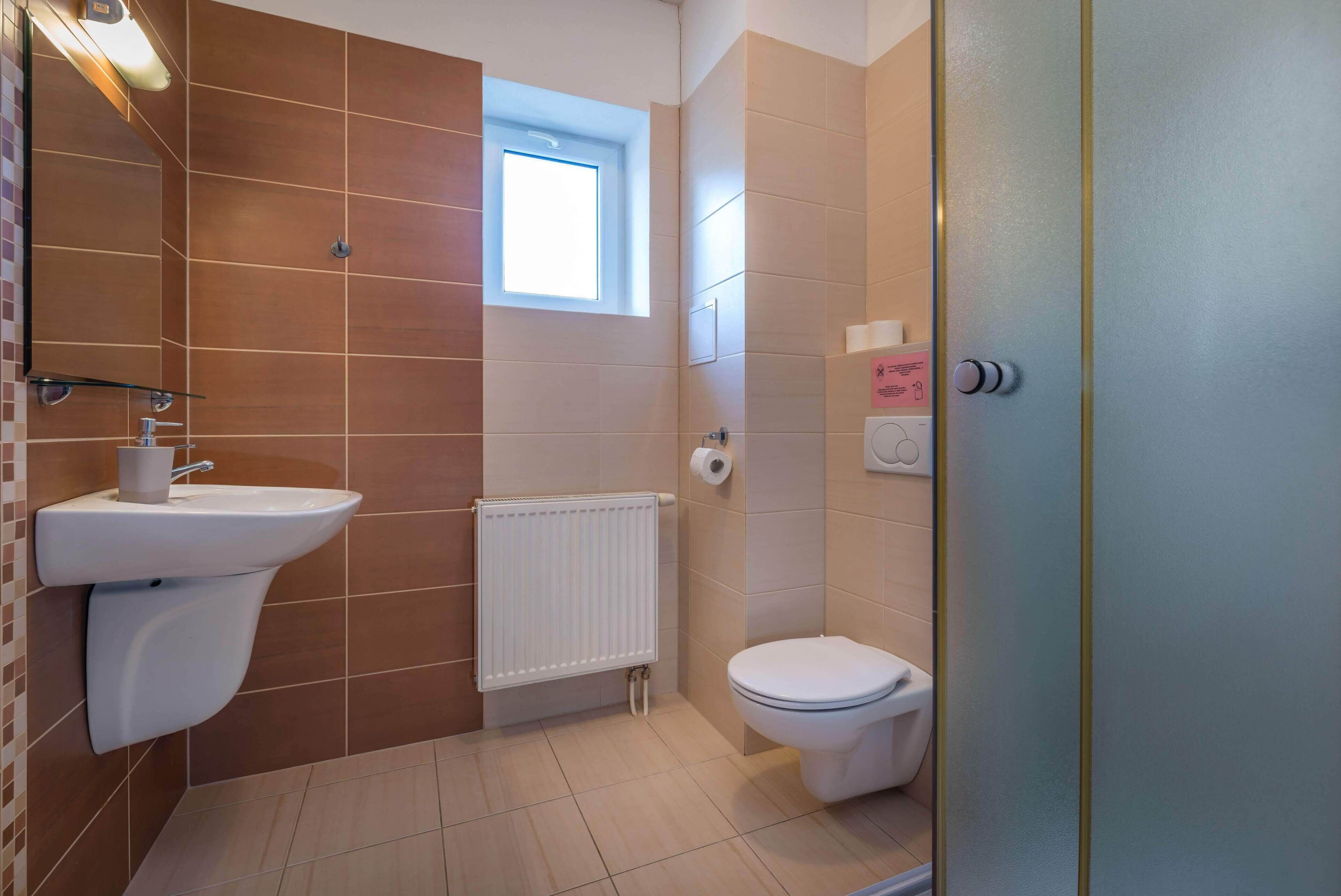 A bathroom with a sink, toilet, and a window.