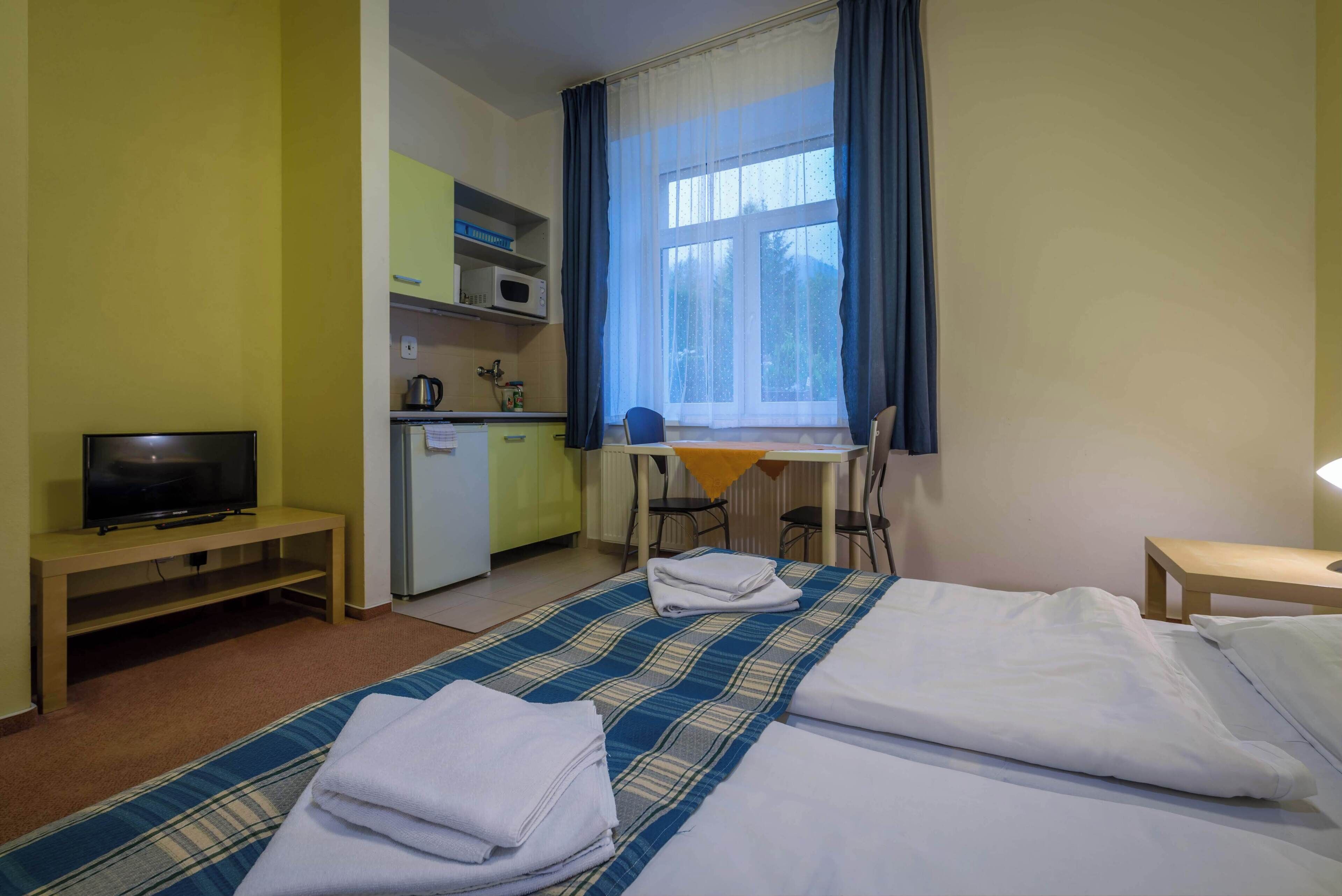 Una camera d'albergo con un letto, una scrivania, una televisione e un angolo cottura.