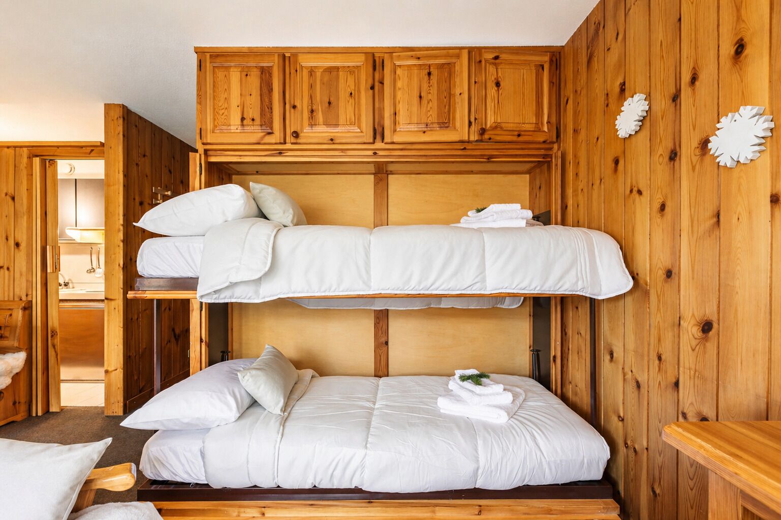 A bunk bed room with wooden walls and cabinets.