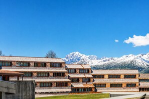 A multi-story wooden building with a mountain backdrop. - Petit Chalet Pila- Apartment on the slopes (Pila)