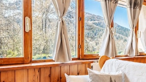 Ein gemütliches Cabin-Zimmer mit Holzvertäfelung, einer Couch mit Decke und Blick auf eine verschneite Landschaft durch das Fenster.
