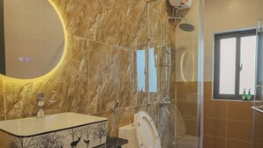 A bathroom with a marble wall, a sink with a tree design, a toilet, a shower, and a window. - TRÀ HOMESTAY CS3 (Hue)