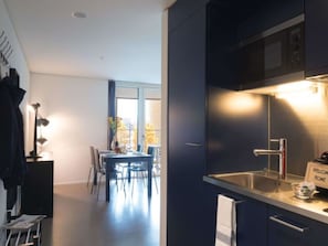 Una cocina moderna con gabinetes oscuros, un lavamanos de acero inoxidable y un cartel que dice 'Welcome Home'.