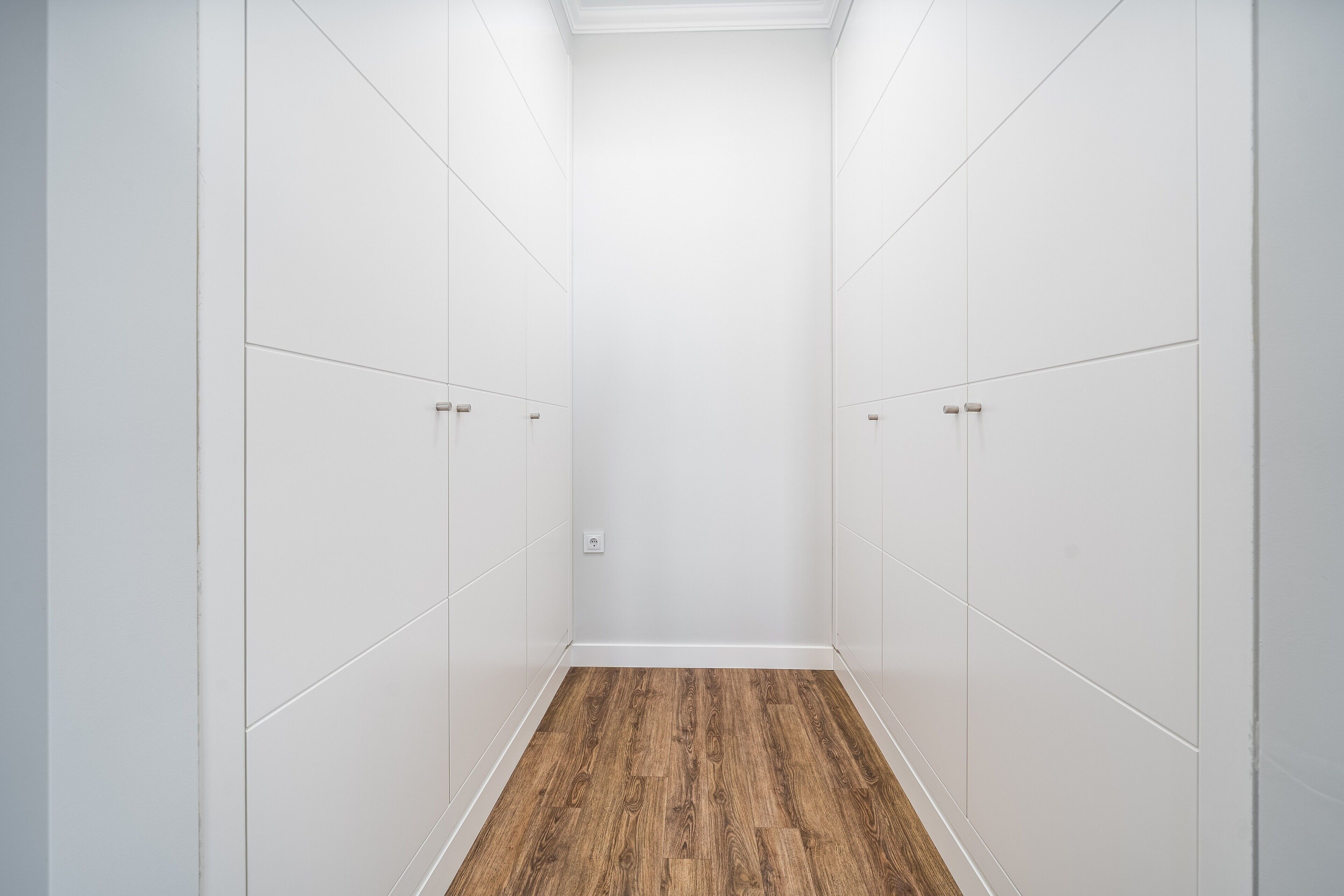 Un dressing avec des murs blancs et un plancher en bois.