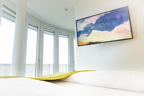 Una habitación de hotel con una cama, un ventanal grande y un cuadro en la pared.