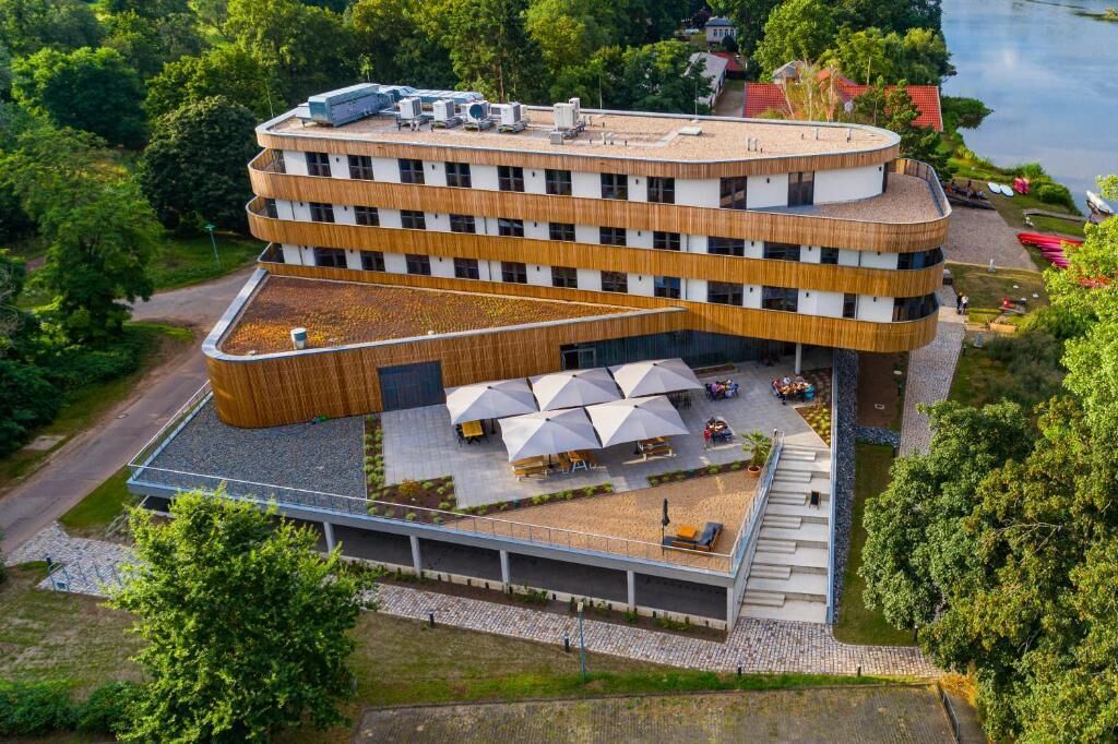 A multi-story building with a curved facade, outdoor seating area, and a covered terrace.