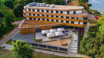 A multi-story building with a curved facade, outdoor seating area, and a covered terrace.