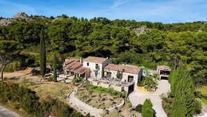 Une villa avec une façade en pierre, de nombreuses pièces et une allée menant à un garage.