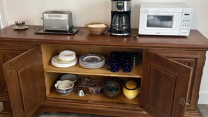 A wooden cabinet with kitchen appliances and dishes.
