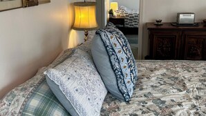 A bedroom with a bed, a nightstand, a lamp, a dresser, and framed pictures on the wall.