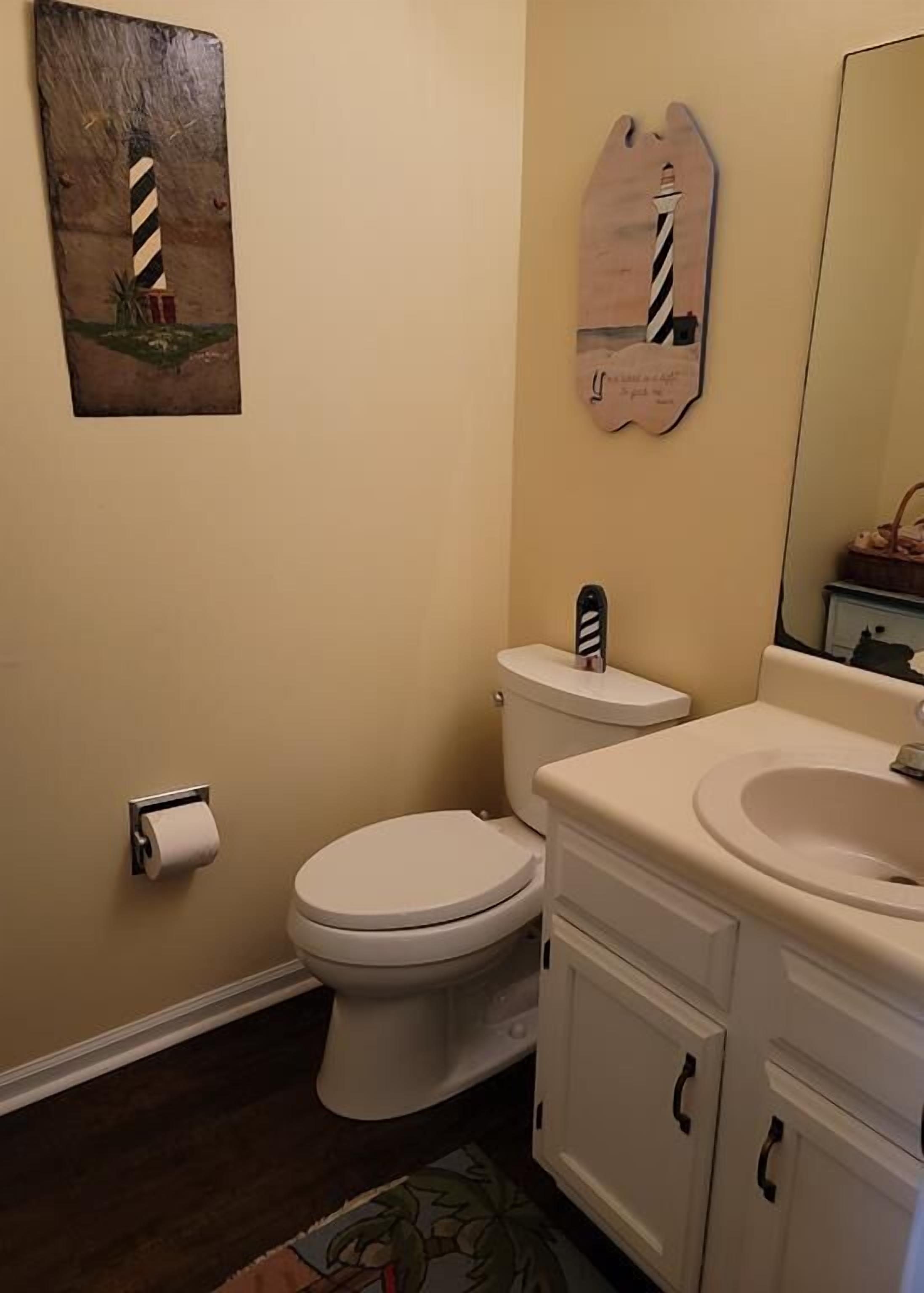 A bathroom with a toilet, sink, and cabinet.
