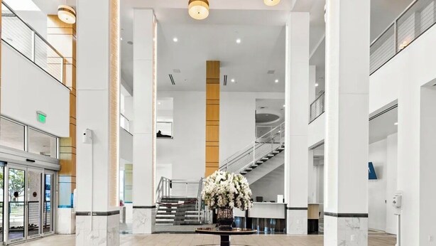 A spacious lobby with a central floral arrangement, a staircase, and a reception desk. - Charming apartment in beautiful Fort Myers perfect for your getaway (Fort Myers)