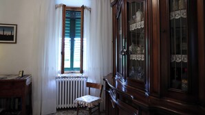 Een kamer met een houten kast, een radiator, een stoel en een raam met gordijnen.