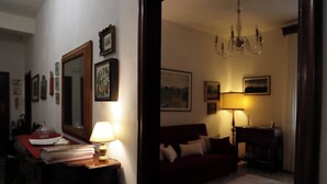 Een kamer met een bureau, lamp, boeken, een spiegel en een rode bank.