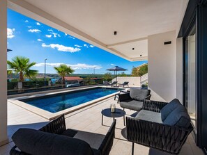 Ein moderner Poolbereich im Freien mit Liegestühlen und Blick auf die Landschaft.