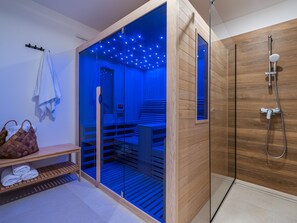 Ein modernes Badezimmer mit einer gläsernen Duschkabine, Holzvertäfelung und einer integrierten Sitzbank mit Handtüchern.