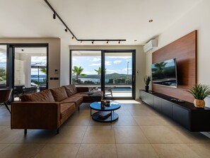 A modern living room with a leather sofa, a round coffee table, and a flat-screen TV mounted on the wall. - Villa S. by Interhome (Posedarje)