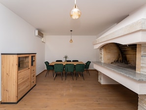 Ein Essbereich mit Holztisch und -stühlen, einer Hängeleuchte und einem Steinkamin.