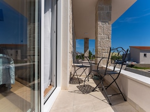 Ein Balkon mit Glastür, Steinpfeilern und Metallstühlen.