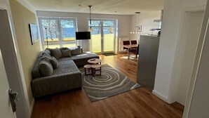 Ein modernes Wohnzimmer mit einer Eckcouch, einem Esstisch und einer Küchenzeile.