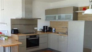 Eine moderne Küche mit Backofen, Kaffeemaschine und Kühlschrank.