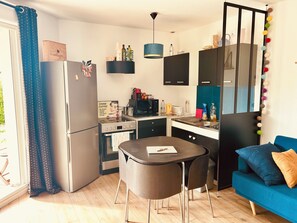 Eine kleine Küche mit Kühlschrank, Mikrowelle, Herd und einem Esstisch.