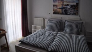 Una camera da letto con un letto, un termosifone, una finestra con tende e un quadro appeso al muro.