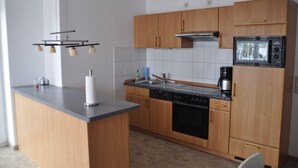 Una cucina moderna con mobili in legno, forno integrato, microonde e macchina per il caffè.