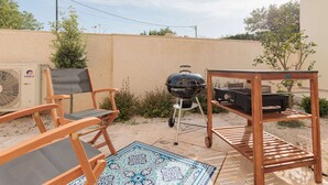 Eine Terrasse im Freien mit Grill, Stühlen und Tisch.