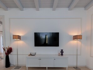 Ein modernes Wohnzimmer mit einem flachbildfernseher an der Wand, der von zwei Stehlampen flankiert wird.