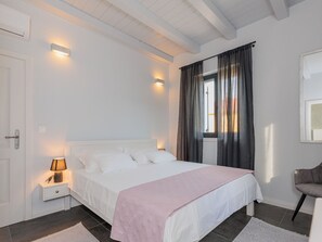 Ein Schlafzimmer mit einem Bett, einer Nachttischlampe und einem Fenster mit Vorhängen.