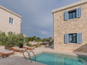 A pool area with lounge chairs and a stone building with shutters. - Seafront Villa Adriatica with pool by Interhome (Pašman/Neviđane)