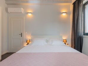 A hotel room with a bed, two bedside lamps, an air conditioning unit, and a window with curtains. - Seafront Villa Adriatica with pool by Interhome (Pašman/Neviđane)