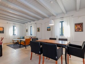 A modern living room with a dining area, featuring a large wooden table, black chairs, a sofa, and a ceiling with exposed beams. - Seafront Villa Adriatica with pool by Interhome (Pašman/Neviđane)