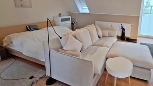 Moderni makuuhuone, jossa on suuri sänky, sohva, pieni pyöreä pöytä, patteri ja kattovalokuvio.