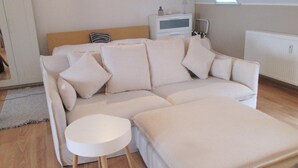 Moderni olohuone, jossa on kulmasohva, pieni pyöreä pöytä ja patteri.