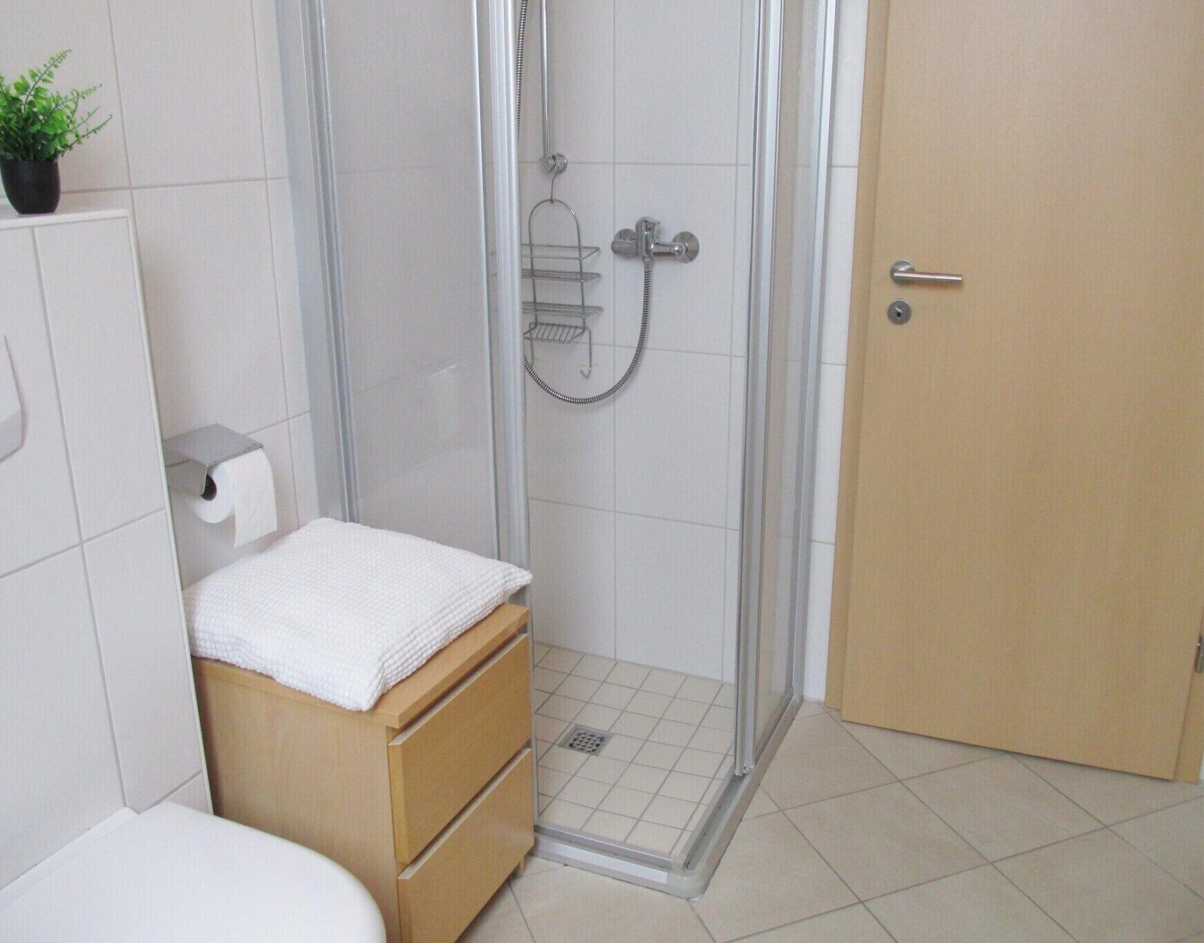 Un bagno con doccia, servizi igienici e un armadietto in legno con un asciugamano.