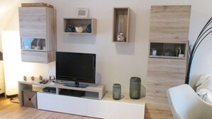 Moderni olohuone, jossa on litteänäyttöinen televisio, seinään upotetut hyllyt ja koriste-esineitä.