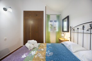 Una camera da letto con un letto, un armadio, un comodino, una lampada e una finestra con tende.