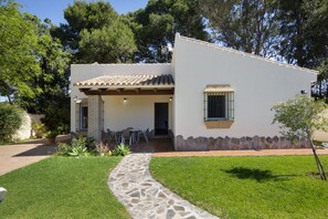 Una casa a un piano con un vialetto in pietra che conduce all'ingresso, circondata da un prato curato e alberi.