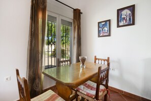 Un'area pranzo con un tavolo e sedie in legno, una finestra a vetro e due quadri appesi al muro.