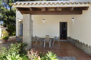 Una terrazza esterna con tavolo e sedie, circondata da piante in vaso e un muro in pietra.