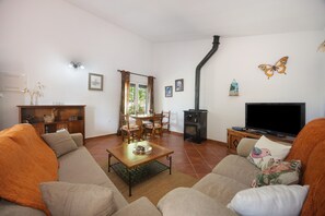 Ein Wohnzimmer mit einer Couch, einem Couchtisch, einem Fernseher, einem Kamin und einem Essbereich mit Stühlen und Tisch.