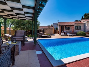 A swimming pool with lounge chairs and a covered seating area. - Stone villa Tea with pool by Interhome (Posedarje)